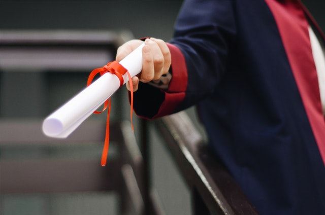 Person holding a graduation diploma.