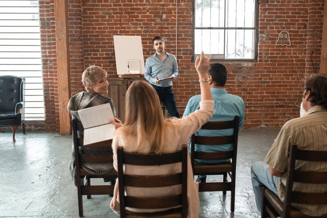 Woman raising her hand to show initiative during a work meeting.