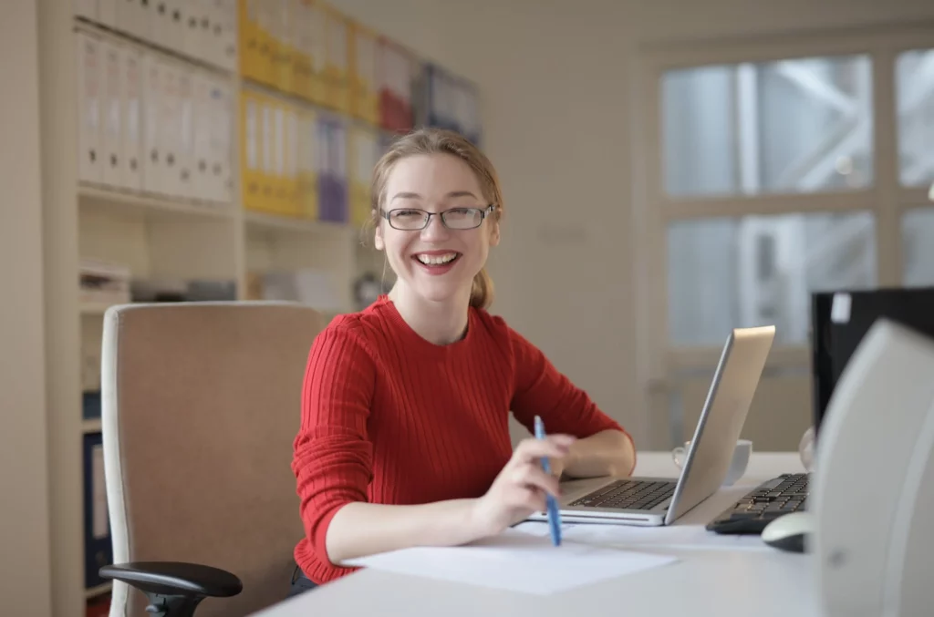 A student in red at a desk smiling