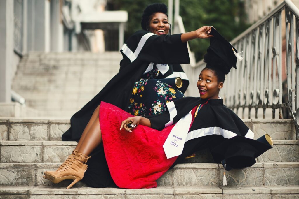 Two college graduates having fun and laughing on street steps