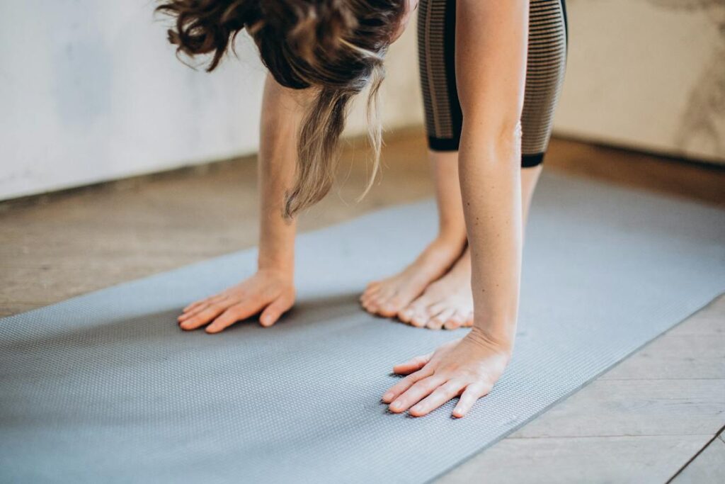 Close-up of woman’s hands on a grey yoga mat 