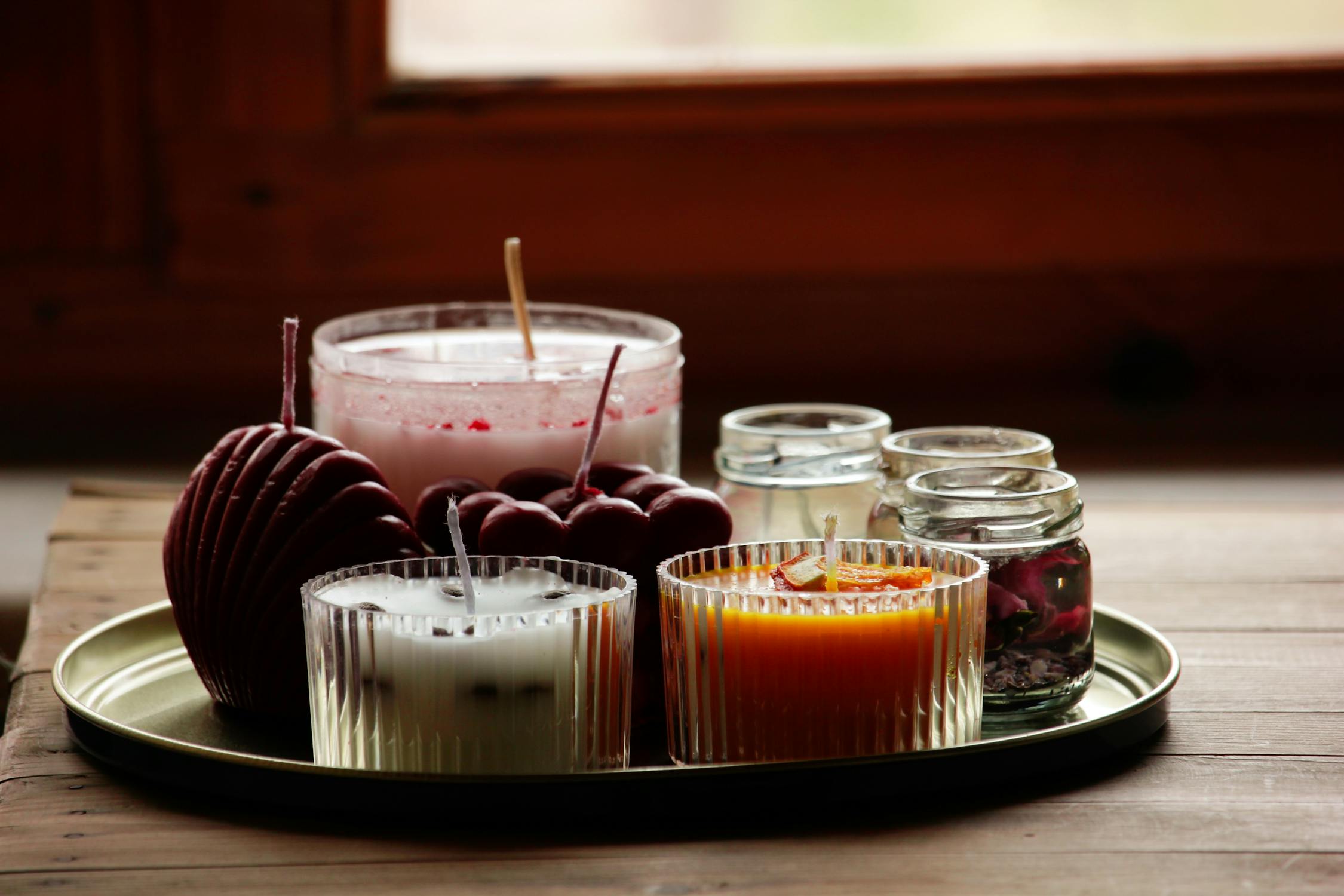 Various colorful scented candles on a tray.